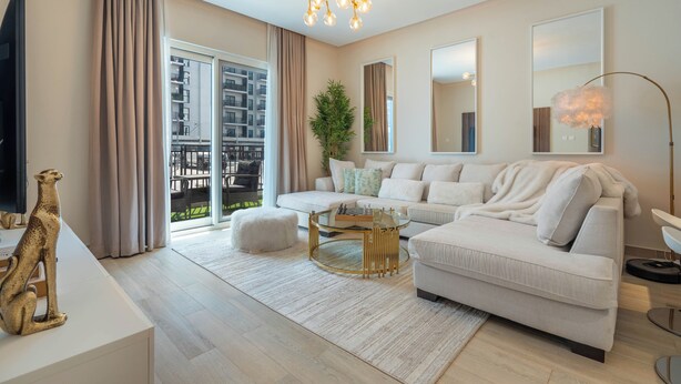 En moderne stue med en hvid sofa, et glasbord og en lysekrone.