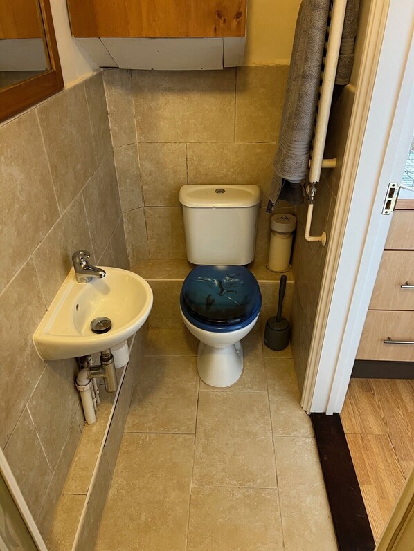 Un baño pequeño con inodoro, lavabo y una toalla colgada en la pared.