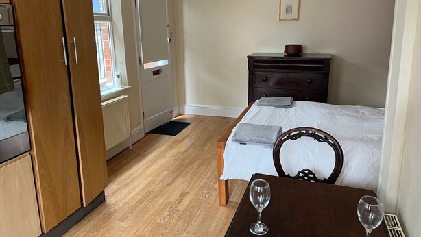 Ein Schlafzimmer mit Bett, Schminktisch, Nachttisch, Fenster und Lampe.