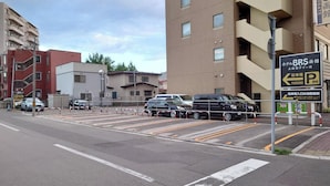 A parking area with multiple cars, a sign indicating BRS hotel, and a building with multiple floors.