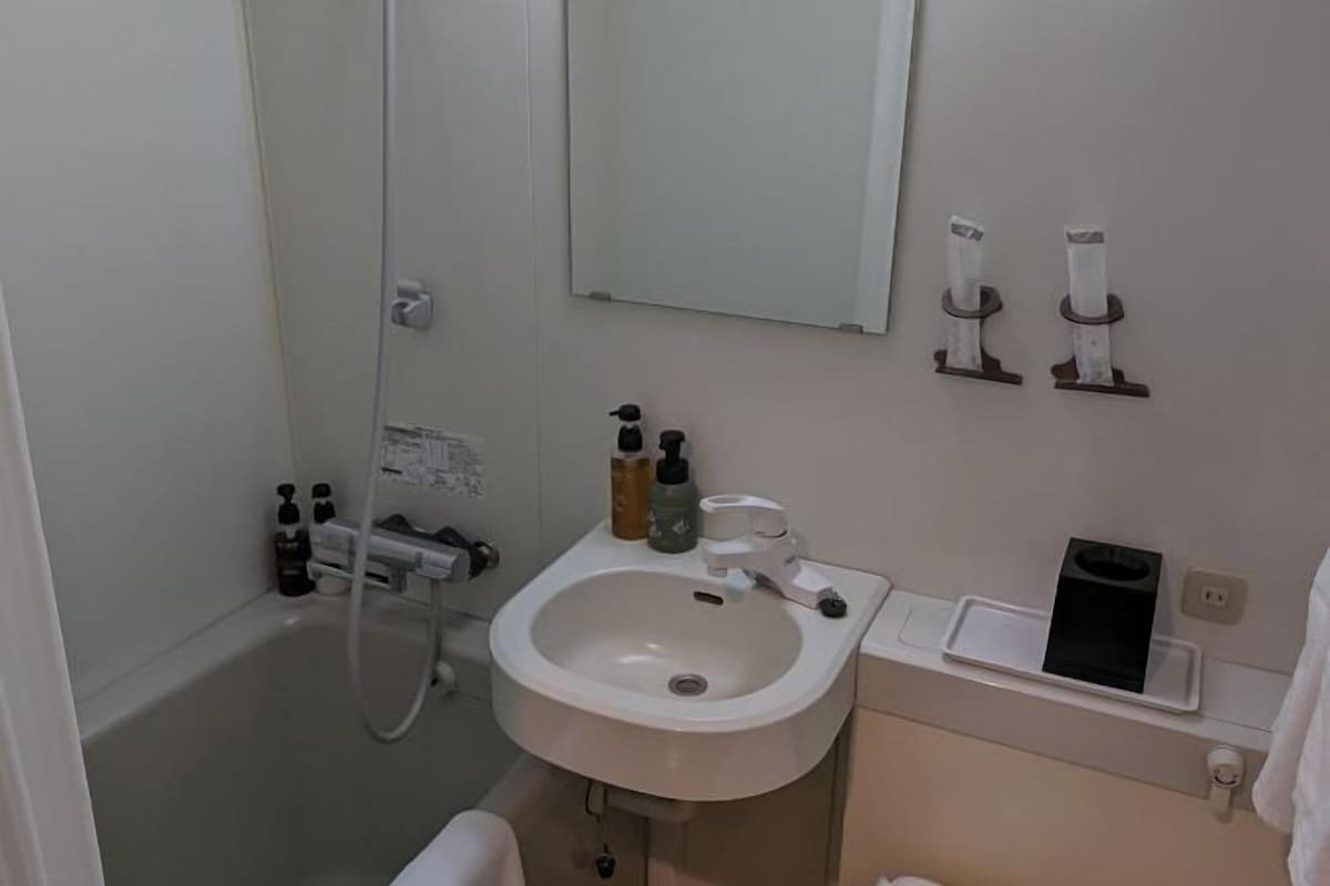 A bathroom with a sink, mirror, towel rack, and shower.