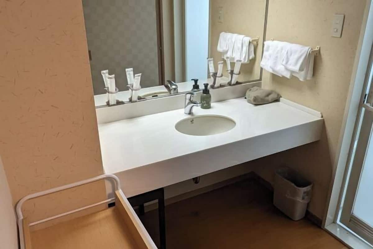 A bathroom with a white sink, mirror, and towel rack.