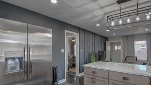 Una cocina moderna con electrodomésticos de acero inoxidable, encimera de mármol y dispensador de agua integrado.