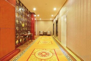 A hotel corridor with a patterned carpet, a wall of framed pictures, and a door at the end. - Zhongheng Zangji Xima Hotel (Nyingchi)