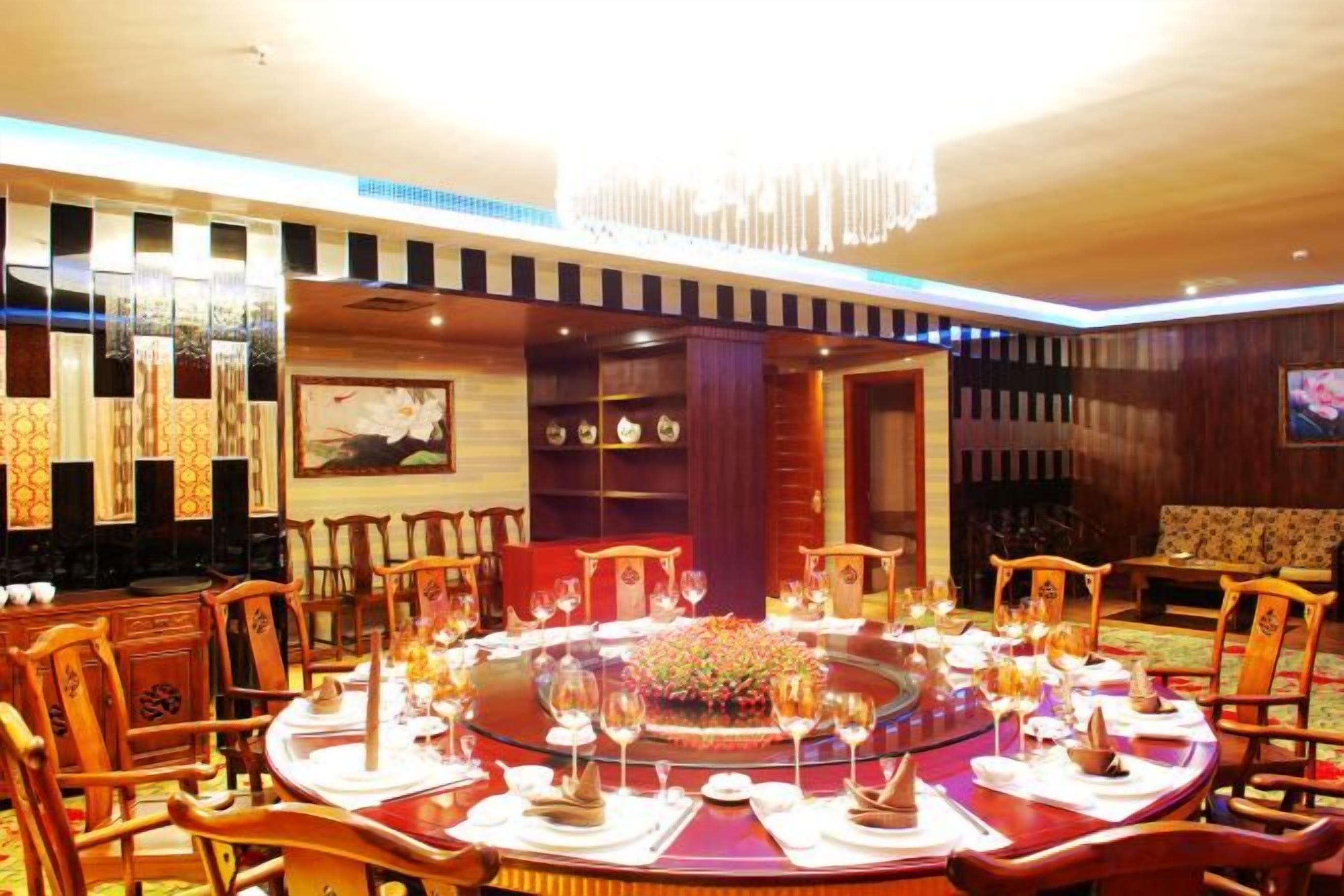 A round dining table with chairs, a chandelier, and a floral centerpiece.
