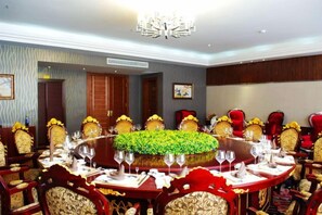 Une salle de conférence équipée d’une table ronde, de chaises et d’un lustre.
