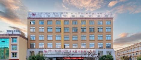 A multi-story hotel with a flat facade, large windows, and a signboard at the entrance.