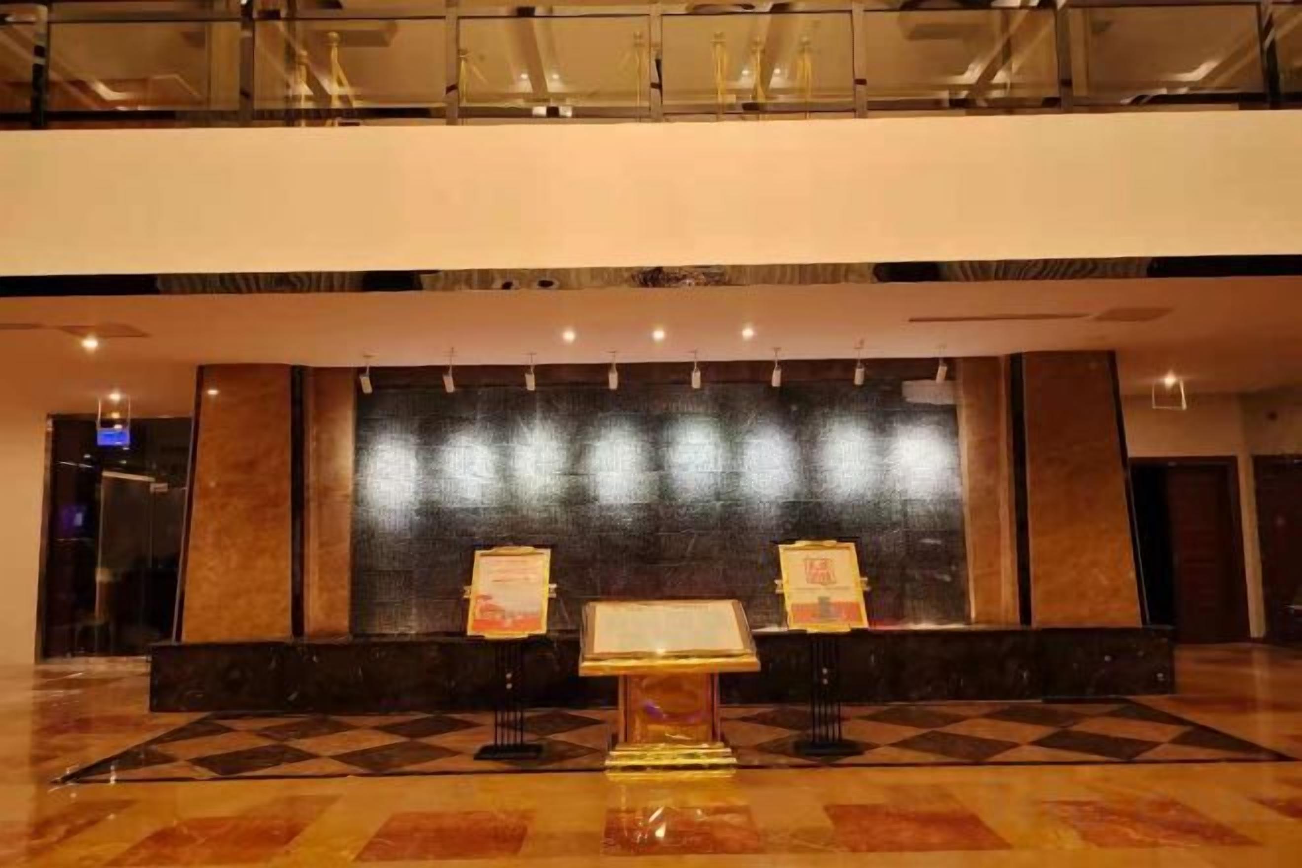 A lobby with a checkered floor, a reception desk, and a wall with a reflective surface.