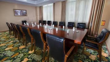 Un salón de conferencias con una larga mesa, sillas y una alfombra estampada.