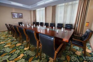 Un salón de conferencias con una larga mesa, sillas y una alfombra estampada.