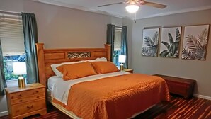 A bedroom with a wooden bed, a nightstand, a ceiling fan, and a window with curtains.