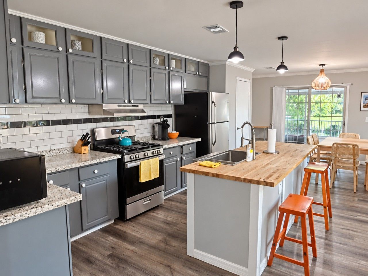 A modern kitchen with grey cabinets, a black stove, and a wooden island with stools.