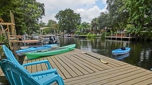 A wooden dock with blue chairs and kayaks.