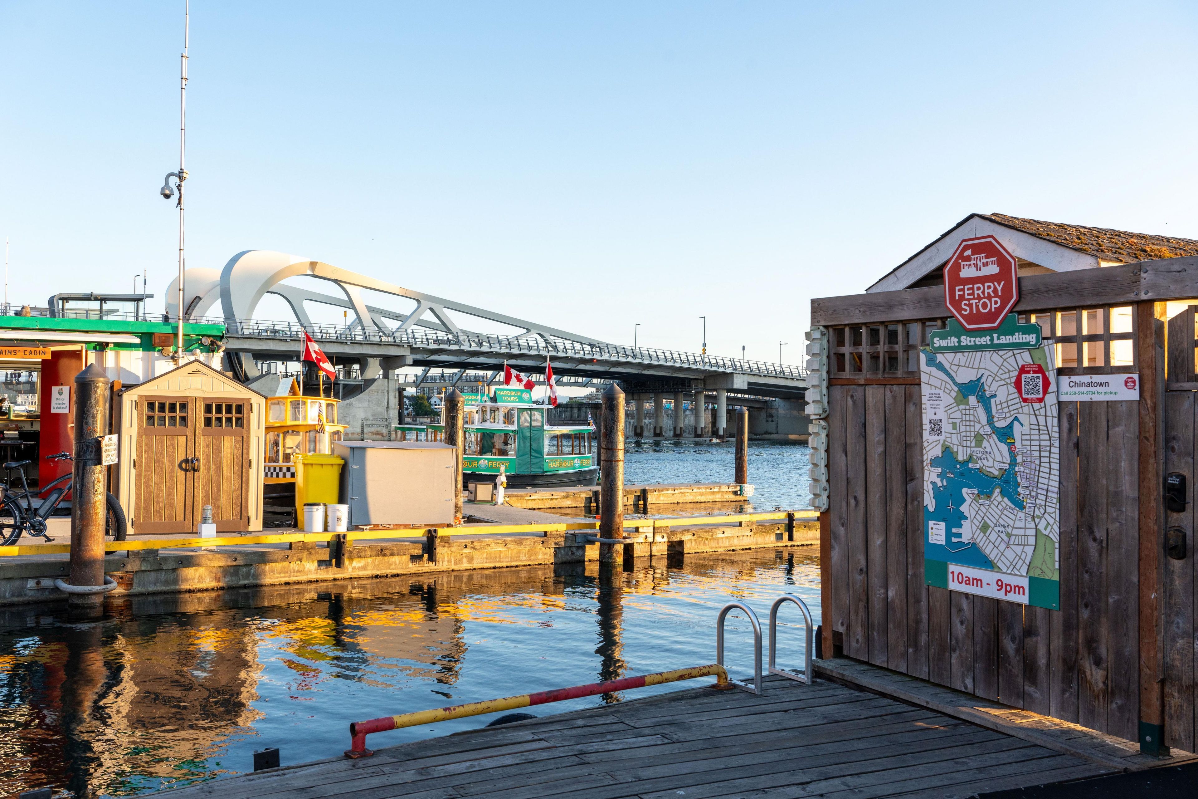 Un quai au bord de l’eau, avec un panneau indiquant l’arrêt du ferry, une carte et un bâtiment en bois.