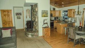 Una sala de estar acogedora con chimenea, un comedor con sillas de madera y una cocina con armarios de madera y una pared de acento de piedra.