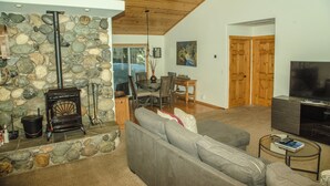 Una sala de estar con chimenea de piedra, un sofá, un televisor y una zona de comedor.
