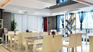A modern dining area with a glass table and white chairs, a brick accent wall, and a staircase with a metal railing. - Penguin Aurora City Hotel (Linhai Chonghemen) (Linhai)