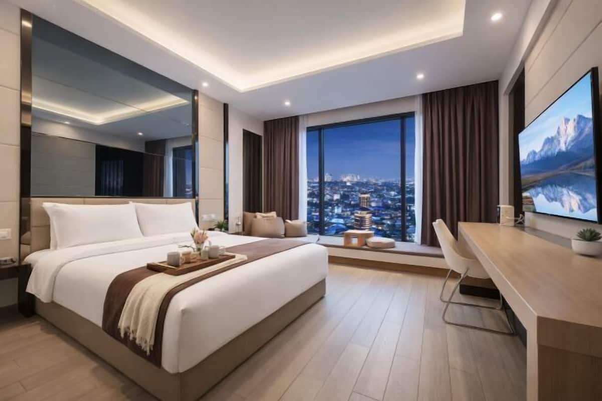 Habitación de hotel moderna con una cama grande, escritorio, televisor y vistas a la ciudad.