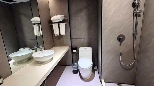 A modern bathroom with two sinks, a toilet, and a shower. - Penguin Aurora City Hotel (Linhai Chonghemen) (Linhai)