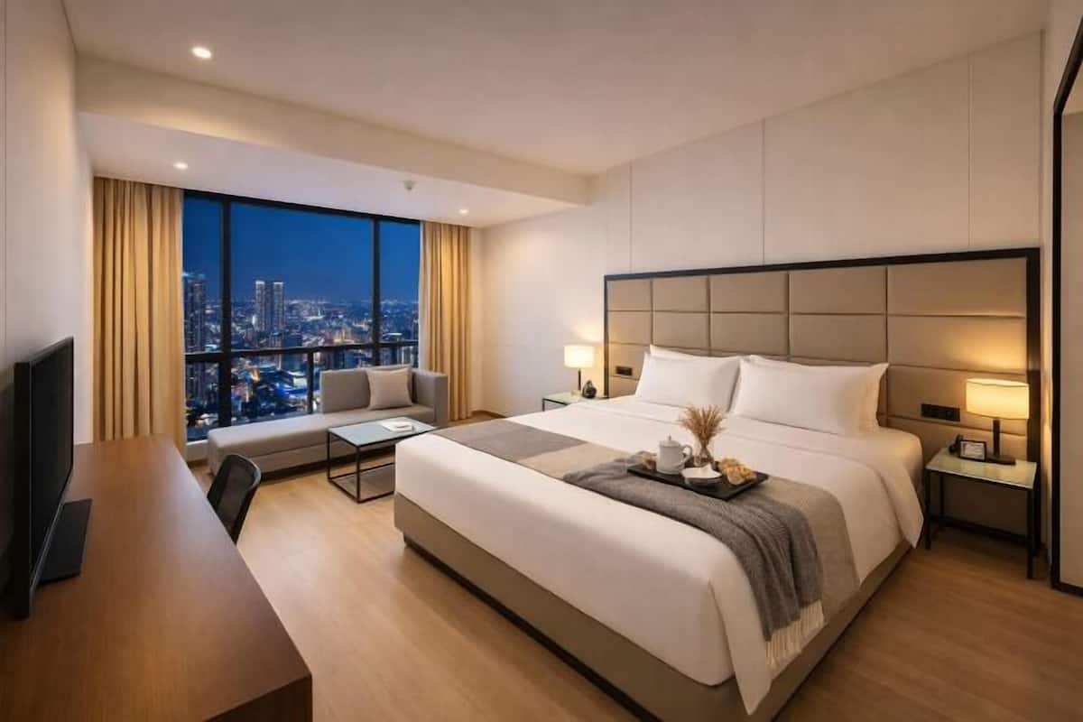 Habitación de hotel con una cama grande, un escritorio, una silla, un televisor y vistas a la ciudad.