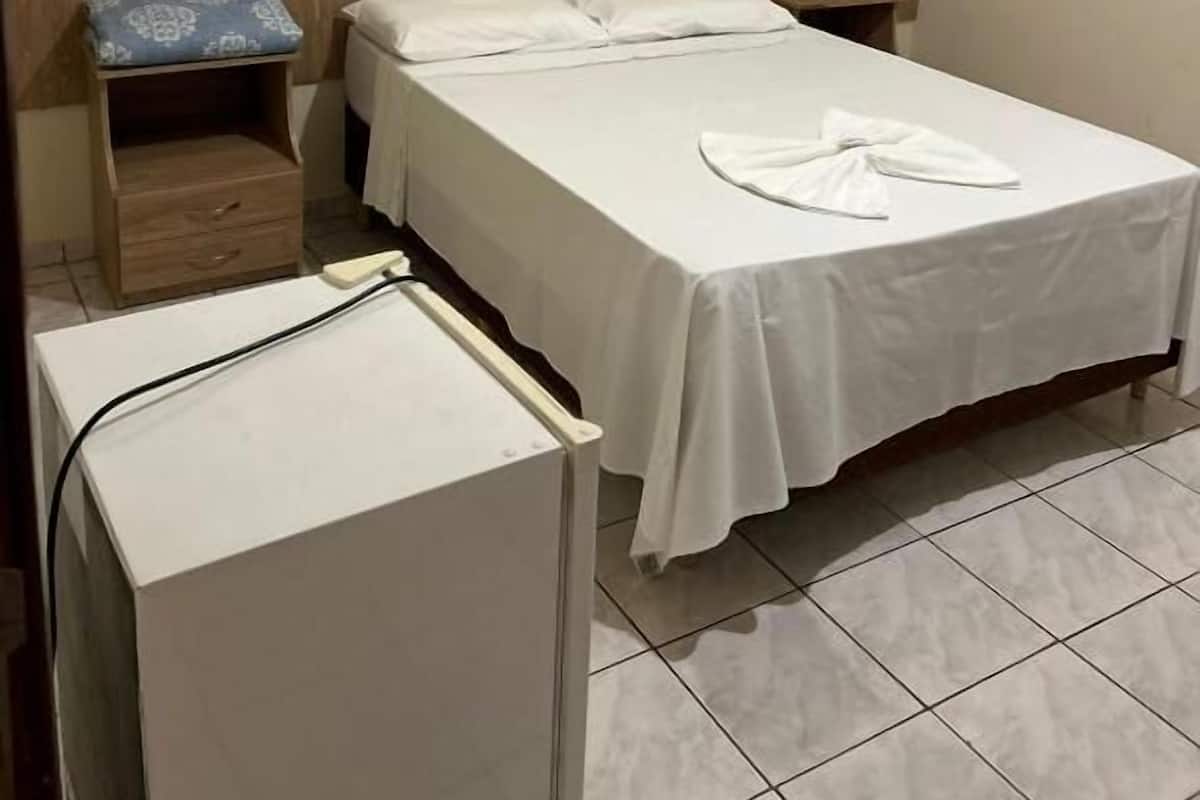 A single bed with a wooden headboard and a small bedside table with a patterned cushion.