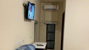 A small, compact room with a bed, a desk, and a television mounted on the wall. - Bravo Inn hotel Coxim (Coxim)