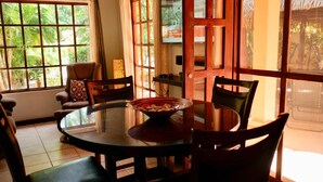 Un coin repas avec une table ronde, des chaises et un saladier rempli de nourriture.
