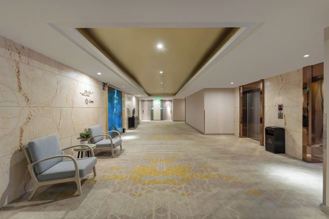 Un vestíbulo de hotel con piso de mármol, zona de estar y ascensores.