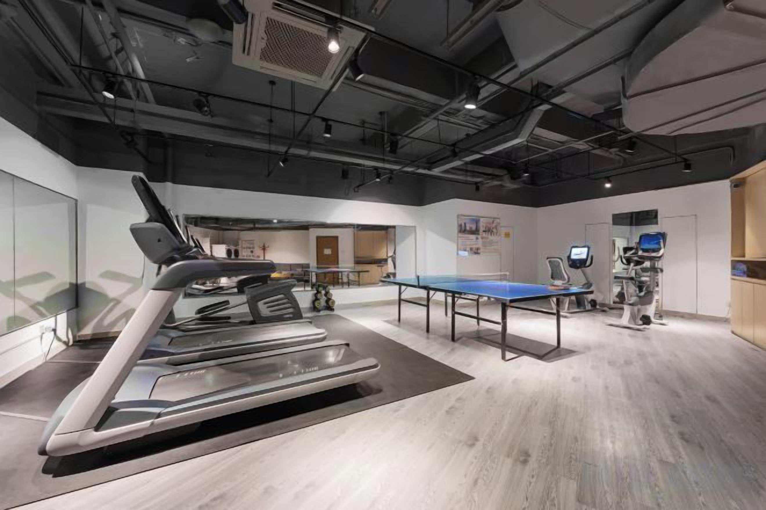 A modern fitness center with a treadmill, exercise ball, and a ping pong table.