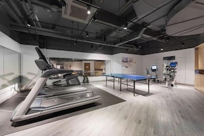 Una palestra moderna con tapis roulant, palla da ginnastica e tavolo da ping pong.