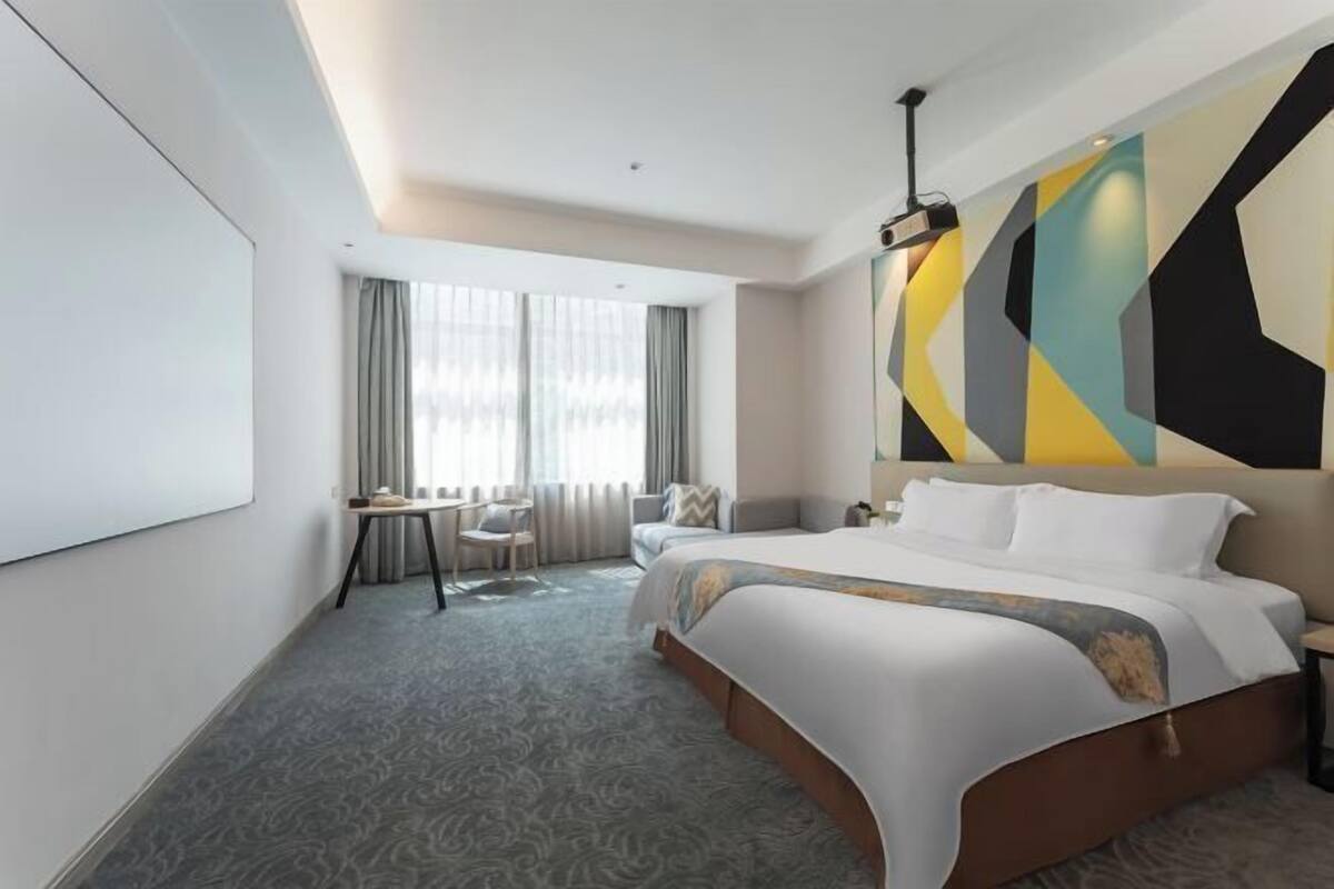 Una habitación de hotel moderna con una cama grande, un escritorio y vistas a la ciudad.