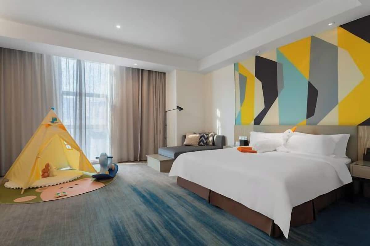 Una habitación de hotel con una cama grande, una tienda de campaña y un diseño geométrico en la pared.