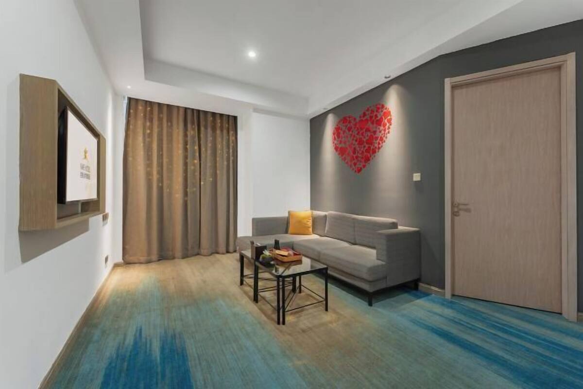 Una sala de estar moderna con un sofá gris, una mesa de centro y una decoración con forma de corazón rojo en la pared.