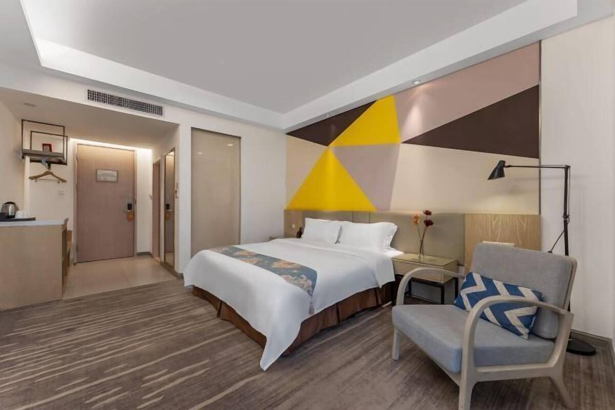 Una habitación de hotel con una cama, una silla, un escritorio y una lámpara.