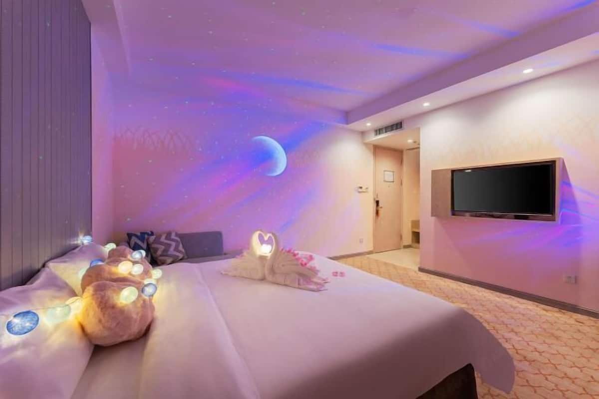 Habitación de hotel con cama, televisor de pantalla plana y techo decorado con motivos celestiales.