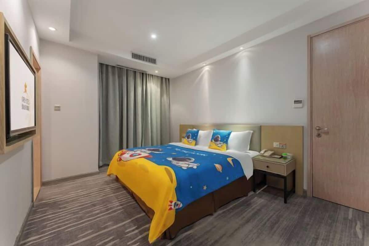 Una habitación de hotel con cama, mesita de noche, escritorio, armario y cortina.