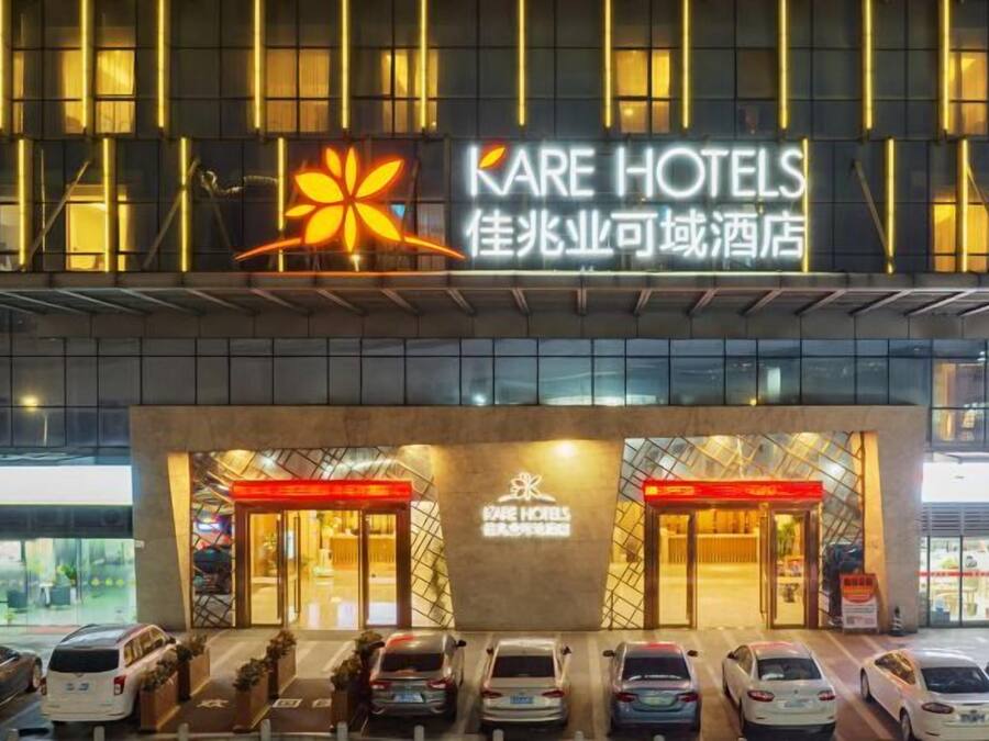 A hotel entrance with a prominent sign, multiple parking spaces, and a modern building facade.