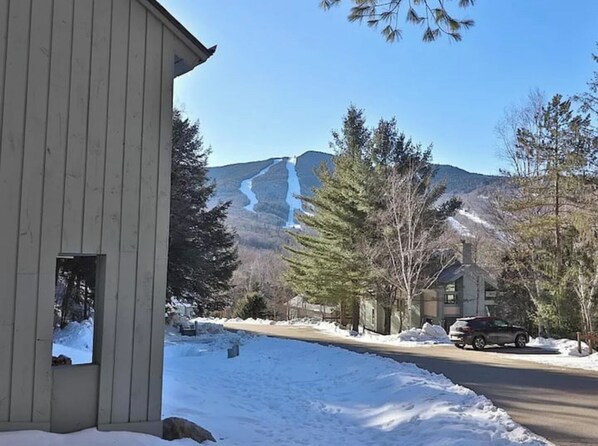 A building with a snow-covered ground and a mountain in the background. - Sleeps 15 | Hike & Ski Loon | Ski Shuttle | Pool + Hot Tub (Lincoln)