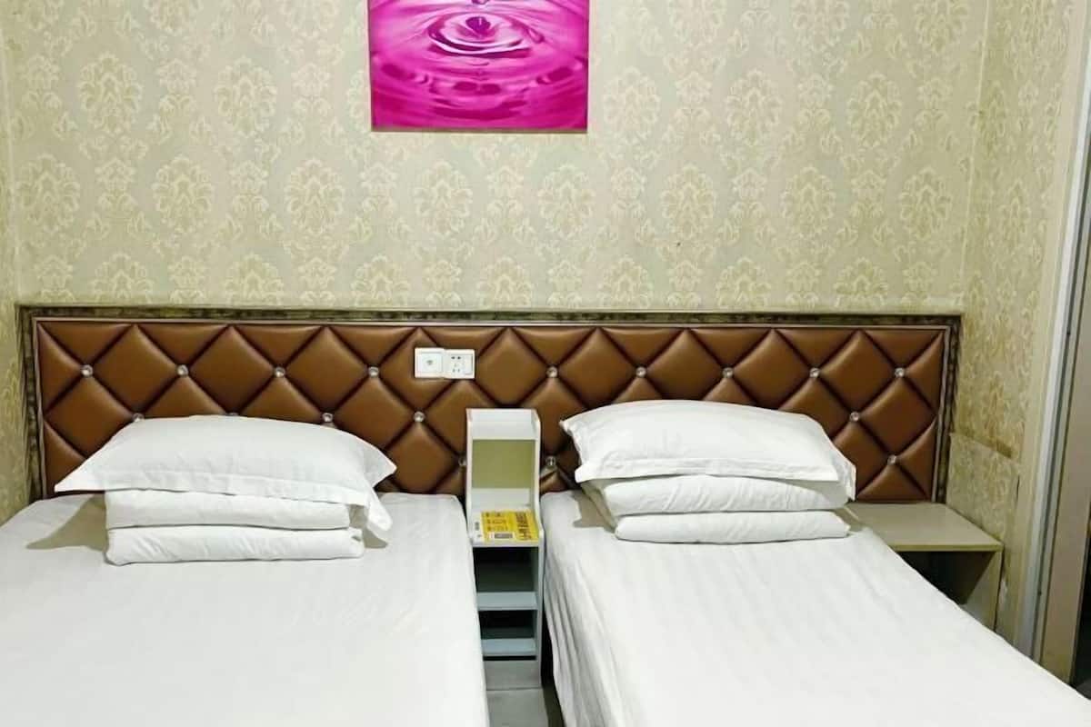 A hotel room with two beds, a brown headboard, and a wall-mounted painting.
