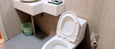 Une salle de bain équipée de toilettes, d’un lavabo et d’une poubelle.