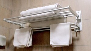 Un baño con un perchero que sostiene varias toallas blancas.