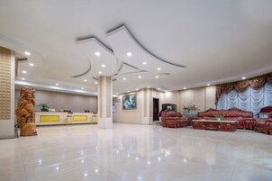Un amplio vestíbulo con mostrador de recepción, un gran conjunto de sofás y un pilar decorativo.