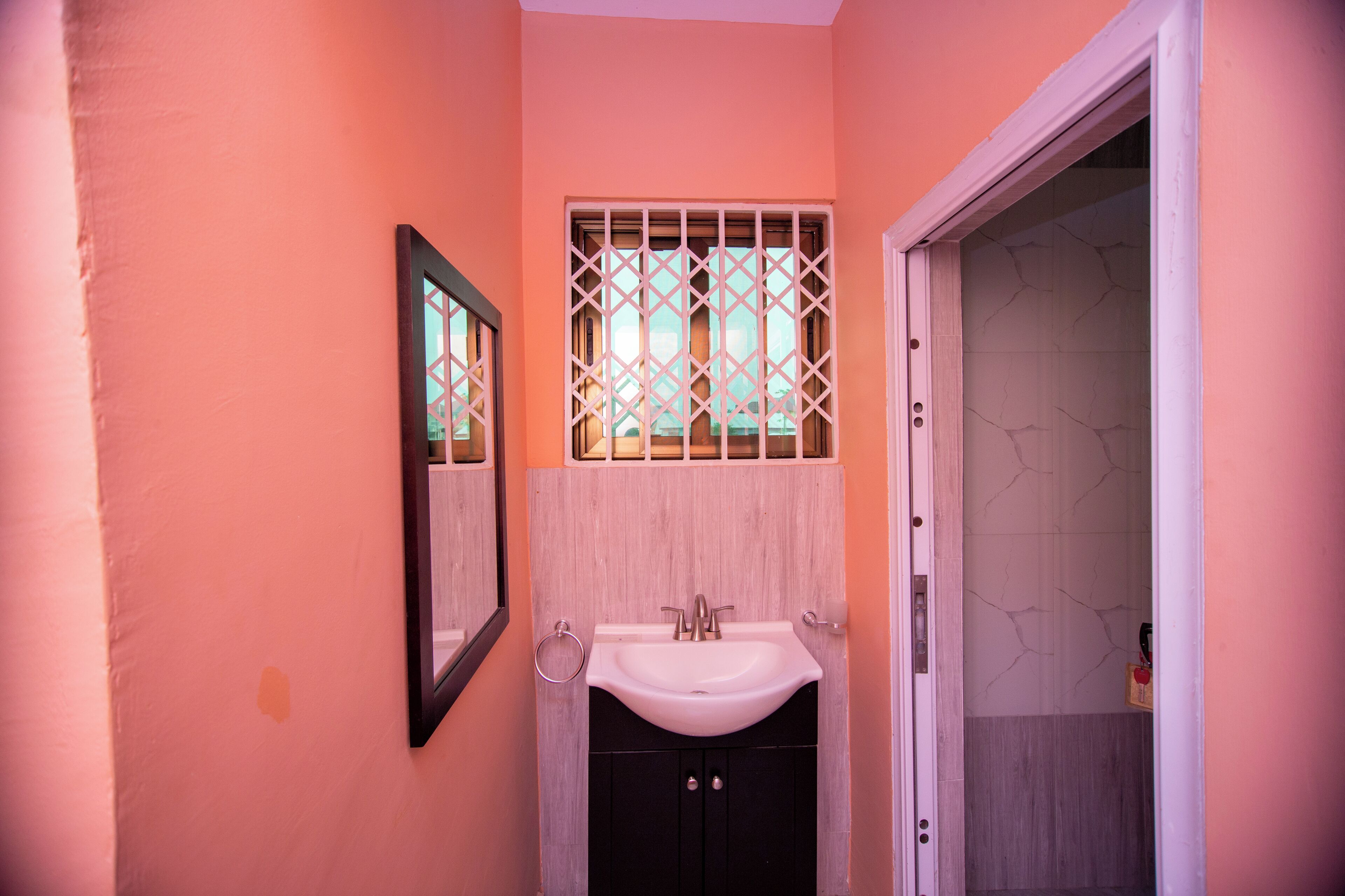 A bathroom with a sink, mirror, and a door leading to another room.