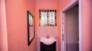 A bathroom with a sink, mirror, and a door leading to another room.