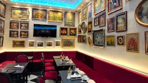 A restaurant with red booths, a TV mounted on the wall, and various framed artworks on the walls. - Victoria Cairo Hotel (Cairo)