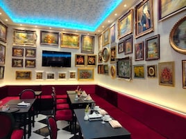 Un restaurante con cabinas rojas, un televisor montado en la pared y varias obras de arte enmarcadas.