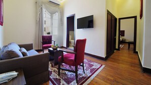 A modern living room with a sofa, a red chair, a flat-screen TV, and a wooden floor. - Victoria Cairo Hotel (Cairo)