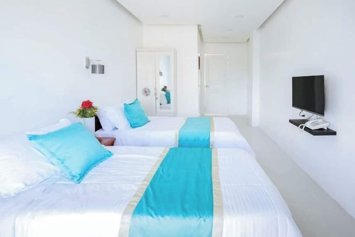 A hotel room with two beds, a TV, and a phone on the wall.