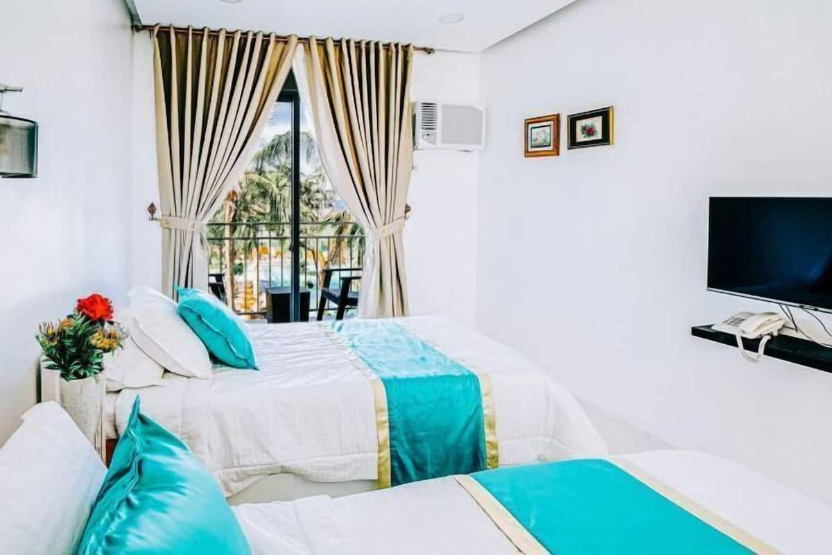 A hotel room with two beds, a TV, and a balcony with a view of palm trees.