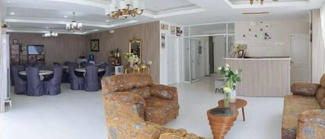 A spacious living area with a dining set, a sofa set, and a reception desk.